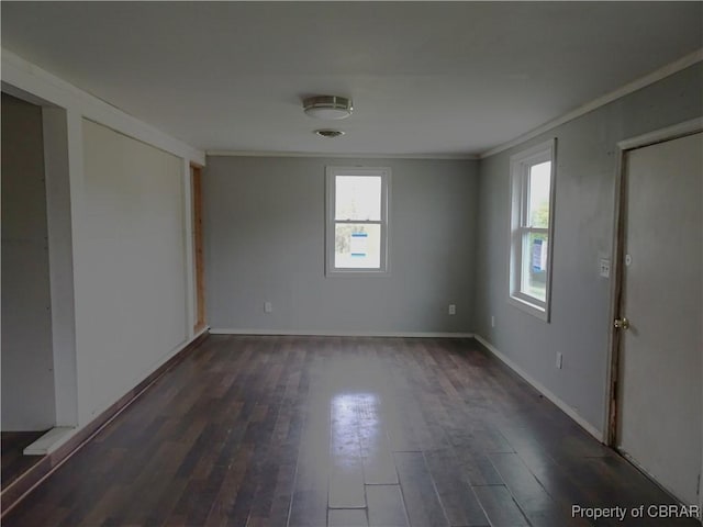 spare room with ornamental molding, dark wood-type flooring, and baseboards