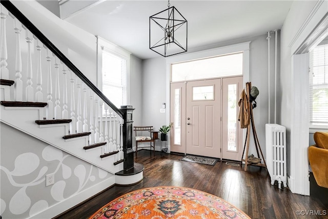 foyer entrance with radiator, dark wood-style floors, stairs, and a chandelier