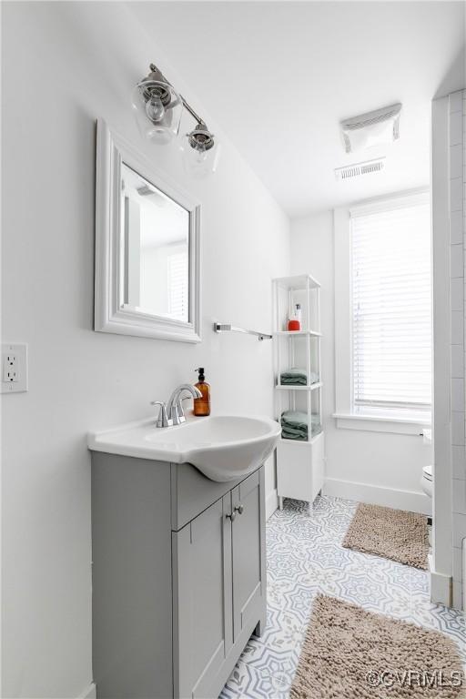 bathroom featuring baseboards, vanity, and toilet