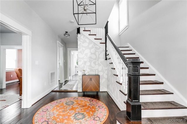 foyer entrance with stairway, wood finished floors, a chandelier, and baseboards