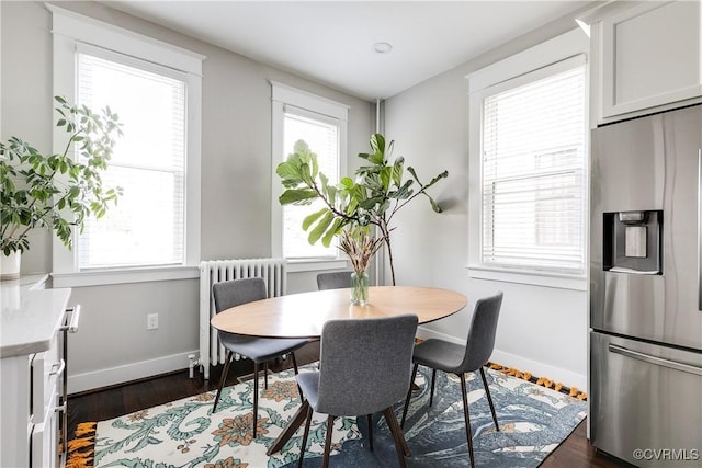 dining space with radiator, baseboards, and dark wood-type flooring
