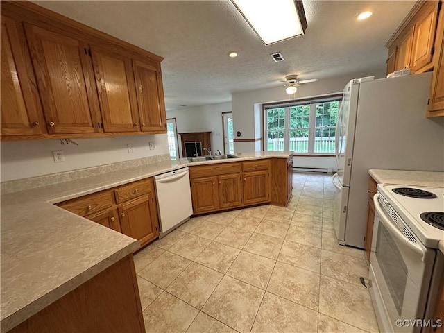 kitchen featuring white appliances, a sink, a peninsula, brown cabinets, and recessed lighting
