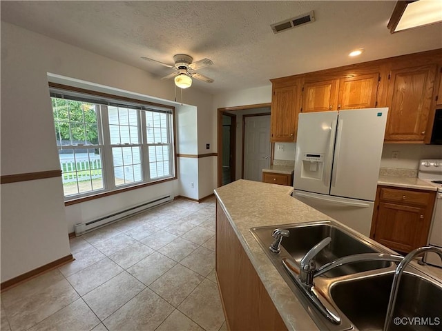 kitchen featuring white appliances, a baseboard radiator, a sink, a ceiling fan, and brown cabinetry