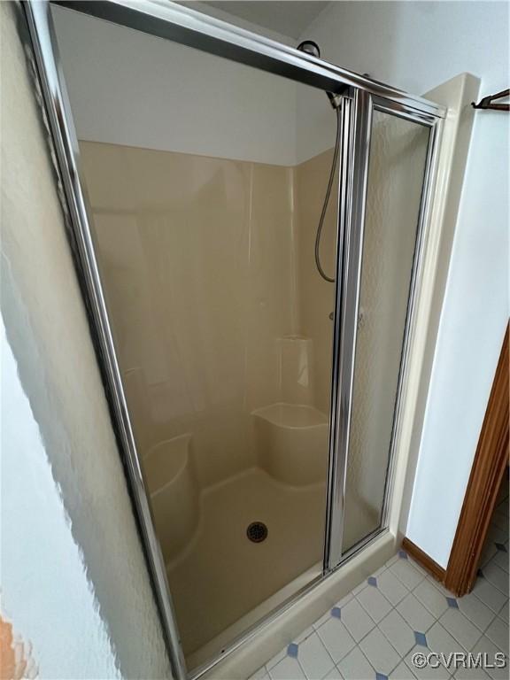 bathroom with a stall shower and tile patterned floors