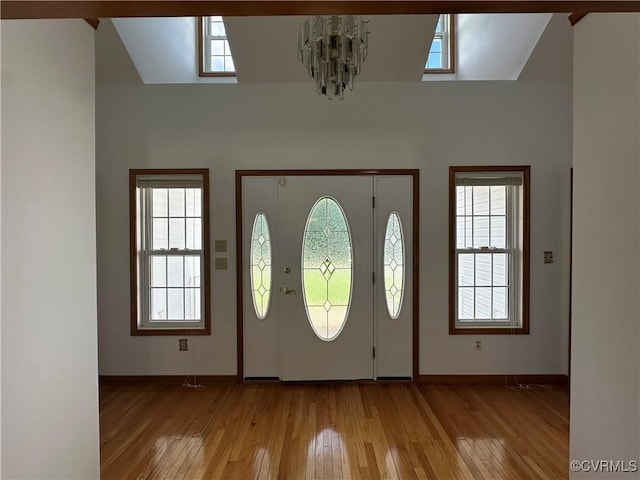 foyer featuring a chandelier, light wood finished floors, baseboards, and healthy amount of natural light