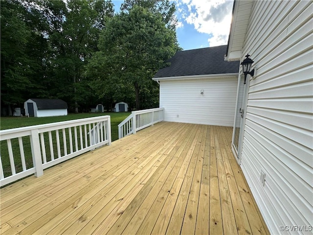 wooden terrace with a storage unit, a lawn, and an outbuilding