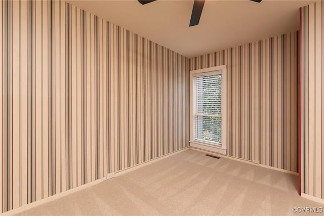 empty room with wallpapered walls, a ceiling fan, and carpet floors