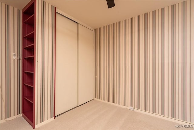 unfurnished bedroom with wallpapered walls, carpet floors, and a closet