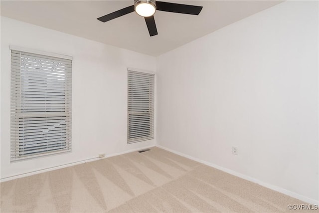 carpeted empty room featuring baseboards and a ceiling fan