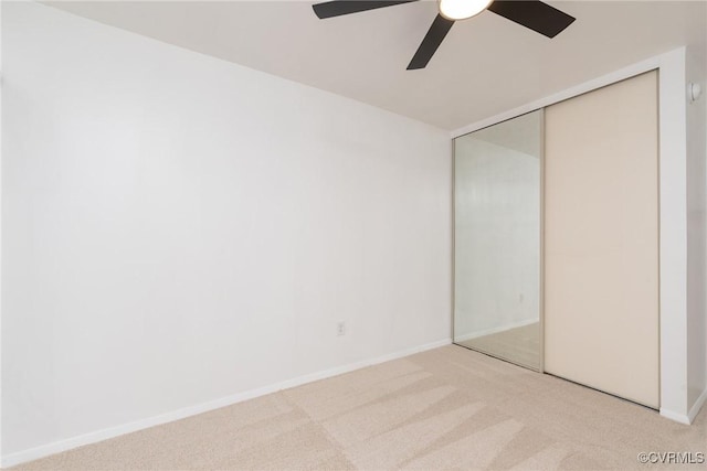 unfurnished bedroom featuring light carpet, a closet, a ceiling fan, and baseboards