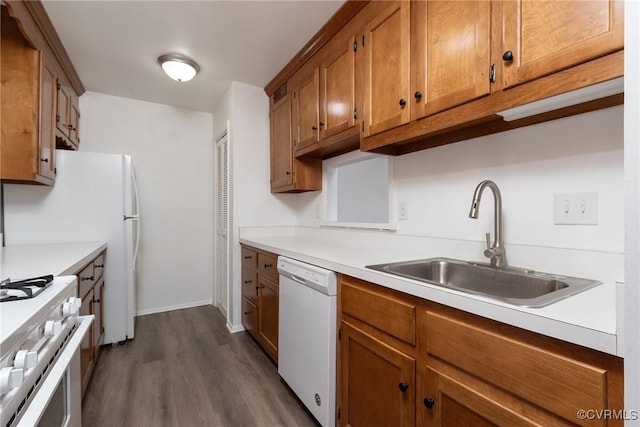 kitchen with white appliances, a sink, brown cabinetry, dark wood finished floors, and light countertops