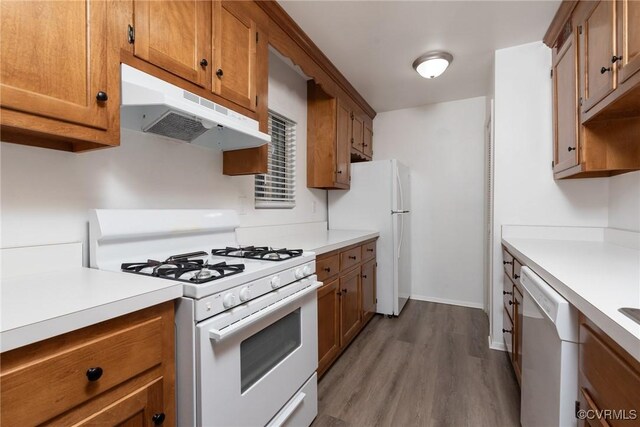 kitchen featuring under cabinet range hood, white appliances, light countertops, brown cabinetry, and wood finished floors
