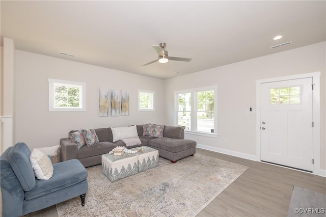 living room featuring wood finished floors, a ceiling fan, and baseboards