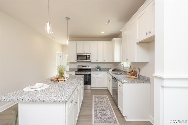 kitchen with stainless steel appliances, a kitchen island, light wood-type flooring, white cabinets, and recessed lighting