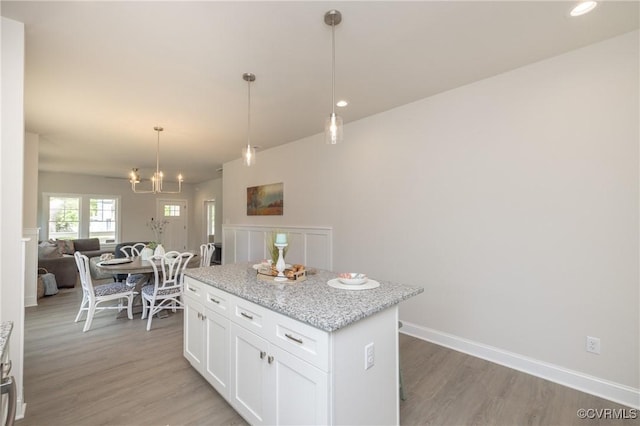 kitchen featuring a center island, light wood-style flooring, white cabinets, open floor plan, and hanging light fixtures