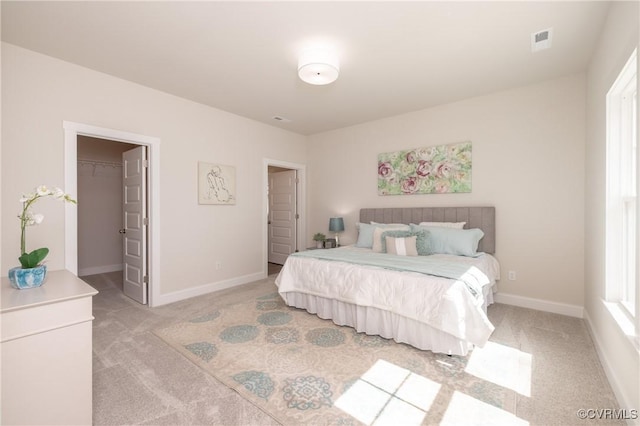 bedroom with light carpet, a spacious closet, and baseboards