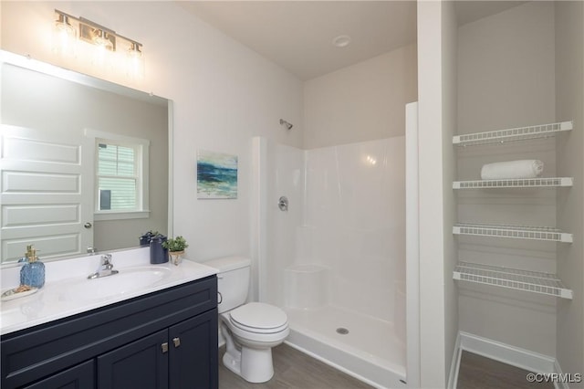 bathroom with toilet, a walk in shower, wood finished floors, and vanity