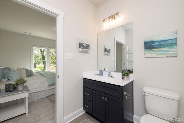 bathroom featuring toilet, ensuite bathroom, vanity, and baseboards