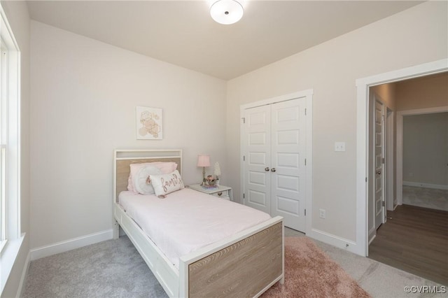 bedroom featuring light colored carpet, a closet, and baseboards