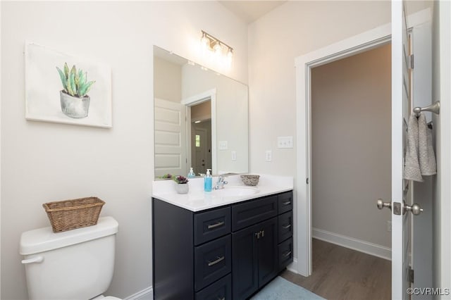 bathroom with wood finished floors, toilet, baseboards, and vanity