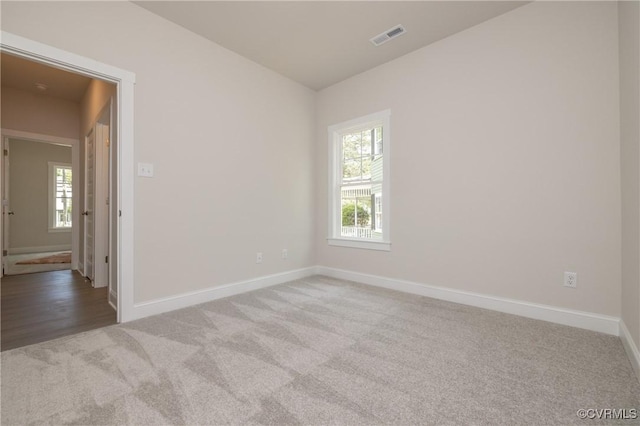 spare room with carpet flooring, baseboards, and lofted ceiling
