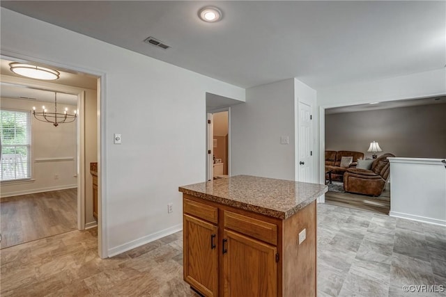 kitchen featuring a chandelier, a kitchen island, baseboards, and brown cabinets
