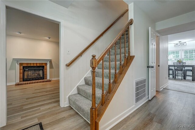 stairway with wood finished floors, a fireplace, and baseboards