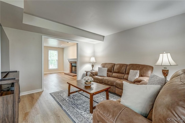 living room featuring a fireplace, light wood finished floors, and baseboards