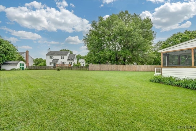 view of yard featuring a shed, an outdoor structure, and a sunroom
