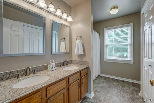 bathroom with baseboards and double vanity