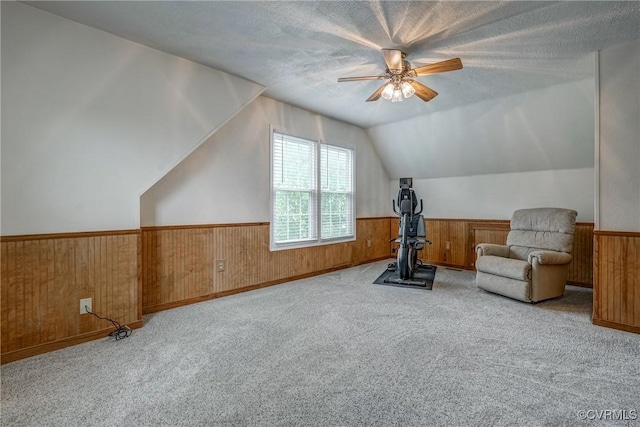 workout area with wood walls, vaulted ceiling, a wainscoted wall, a ceiling fan, and carpet floors