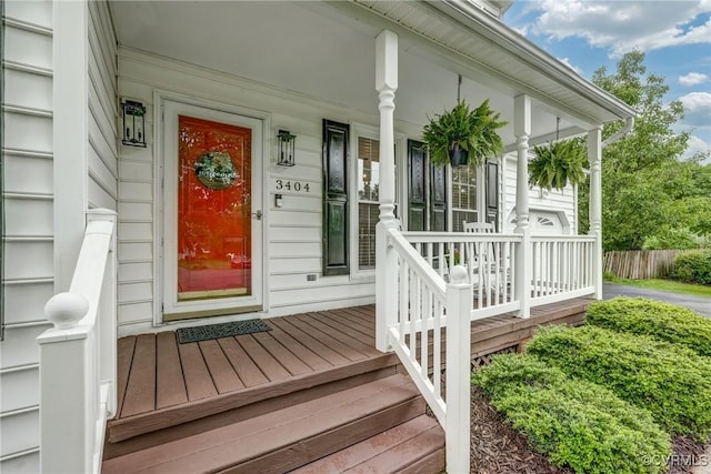 property entrance featuring covered porch and fence