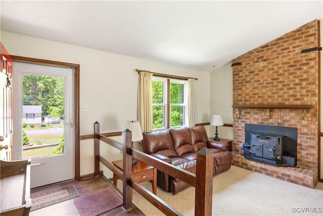 living room with plenty of natural light, lofted ceiling, and a wood stove