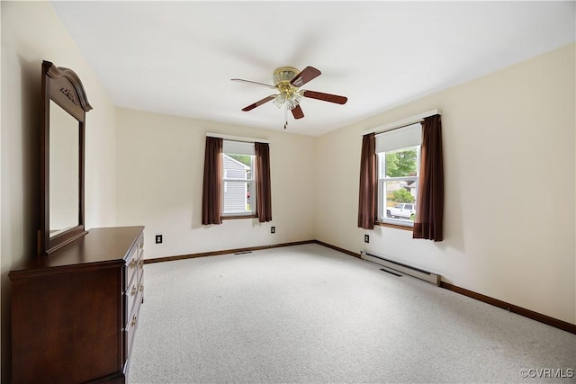 carpeted spare room featuring baseboard heating, baseboards, and a ceiling fan
