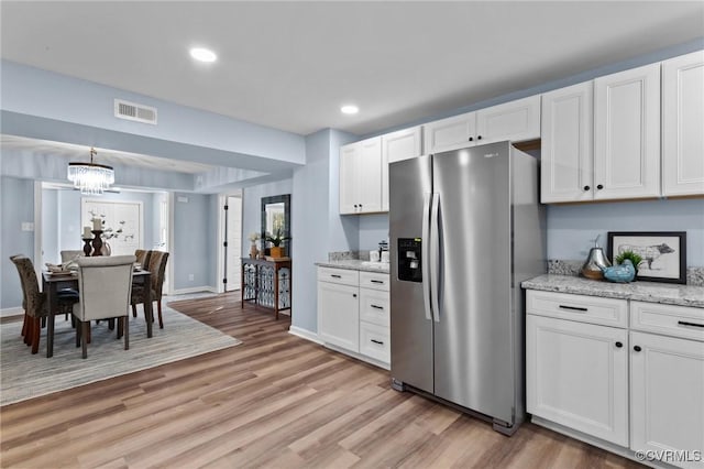 13130 The Glebe Ln, Charles City, VA 23030 - kitchen with stainless steel fridge, light wood finished floors, a chandelier, white cabinetry, and light stone countertops