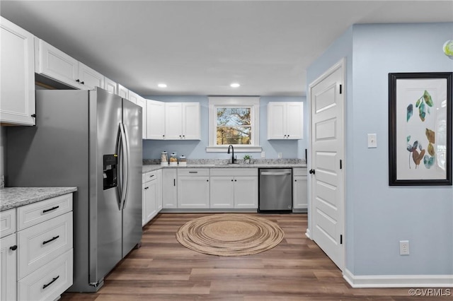 13130 The Glebe Ln, Charles City, VA 23030 - kitchen featuring appliances with stainless steel finishes, a sink, wood finished floors, white cabinetry, and light stone counters