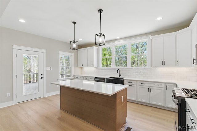 kitchen with appliances with stainless steel finishes, backsplash, light wood-style flooring, a sink, and recessed lighting
