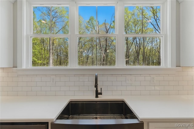 kitchen view of a sink, light countertops, tasteful backsplash, and dishwasher