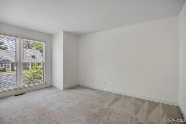 empty room featuring light colored carpet and baseboards