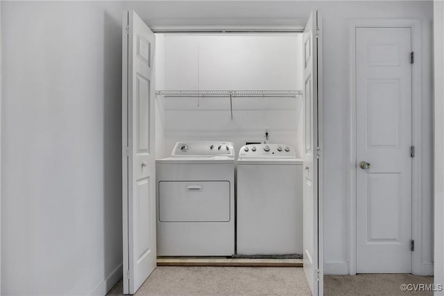 laundry room with washer and dryer and light colored carpet
