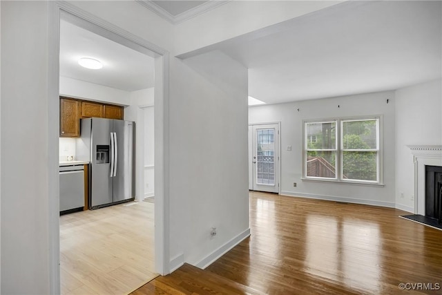 unfurnished living room featuring light wood finished floors, a fireplace, baseboards, and crown molding