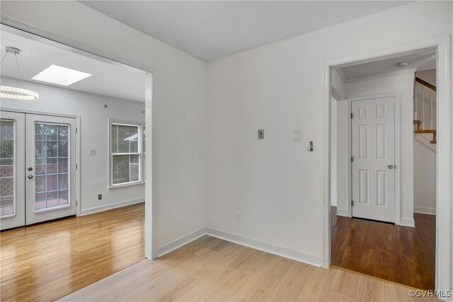 unfurnished room featuring light wood-style flooring, stairway, a skylight, and french doors