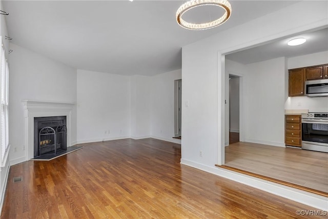 unfurnished living room featuring wood finished floors, baseboards, and a fireplace