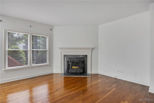 unfurnished living room with wood finished floors, baseboards, and a fireplace