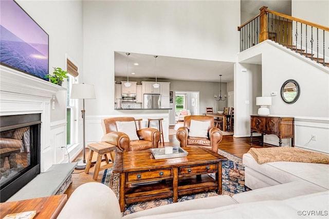 10527 Deerlake Dr, New Kent, VA 23124 - living area with a towering ceiling, a fireplace with raised hearth, wood finished floors, a wainscoted wall, and stairway