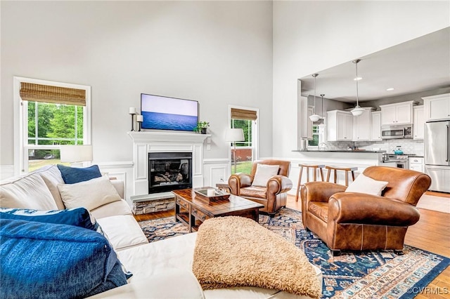 10527 Deerlake Dr, New Kent, VA 23124 - living area featuring wood finished floors, plenty of natural light, a high ceiling, wainscoting, and a glass covered fireplace