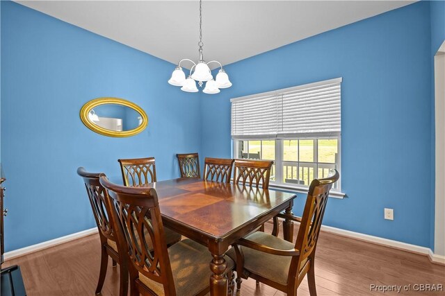 dining space with a chandelier, wood finished floors, and baseboards