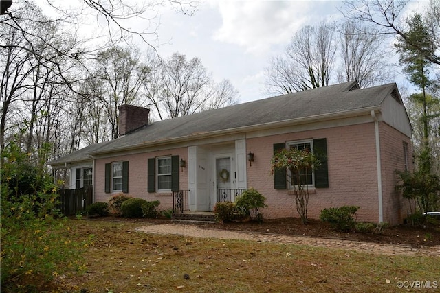 ranch-style home with a chimney and brick siding