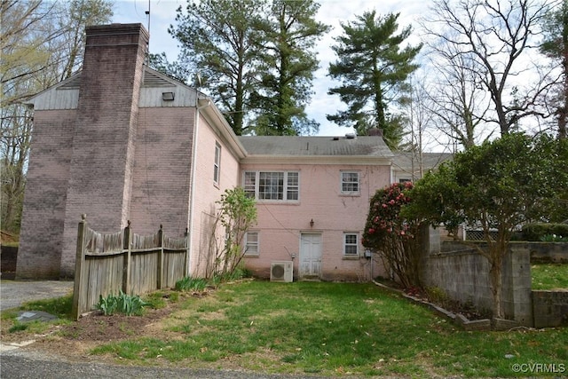 back of property with a chimney, brick siding, and ac unit