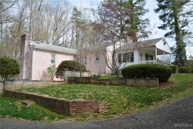 ranch-style house featuring a chimney and a front lawn